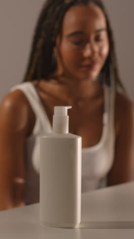 Studio-Skincare-Beauty-Shot-Of-Woman-With-Moisturiser-Bottle-in-Foreground